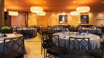A conference room with round tables, black chairs, and overhead lighting.