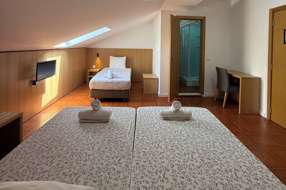 A modern bedroom with a large bed, a desk, and a shower area.