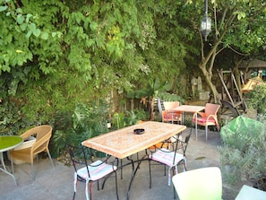 An outdoor patio with a table and chairs, surrounded by lush greenery and a traditional-style lantern. - Pouso Dos Anjos (Lisbon)