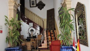 A staircase with a wooden handrail and a chandelier above. There are potted plants on either side of the staircase. - Pouso Dos Anjos (Lisbon)