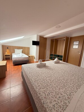 A modern hotel room with a large bed, a desk, a chair, a TV, and a wardrobe. - Pouso Dos Anjos (Lisbon)