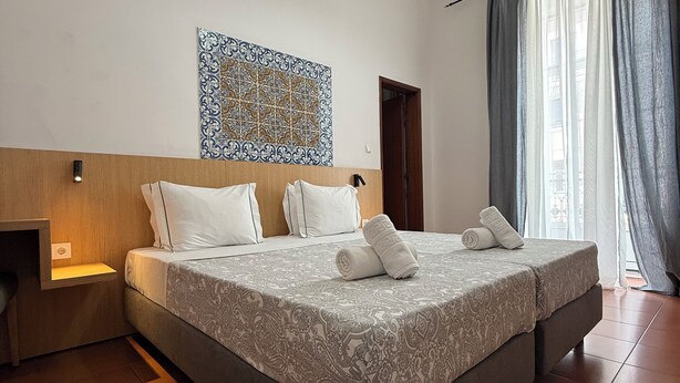 A hotel room with a large bed, a nightstand, a wall-mounted light, and a decorative tile above the bed. - Pouso Dos Anjos (Lisbon)