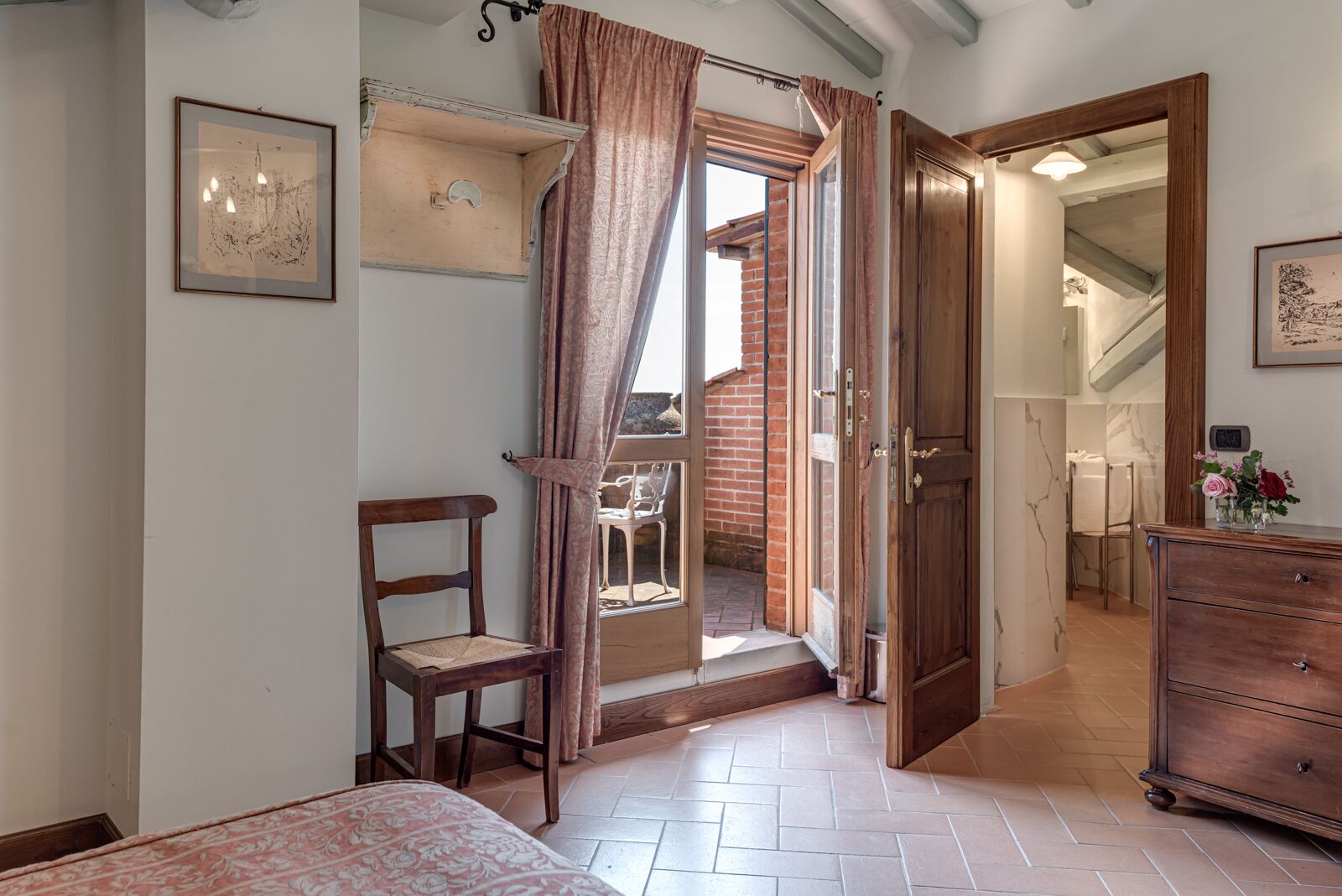 Een kamer met een bed, een houten stoel, een kast en een deur die uitkomt op een balkon.