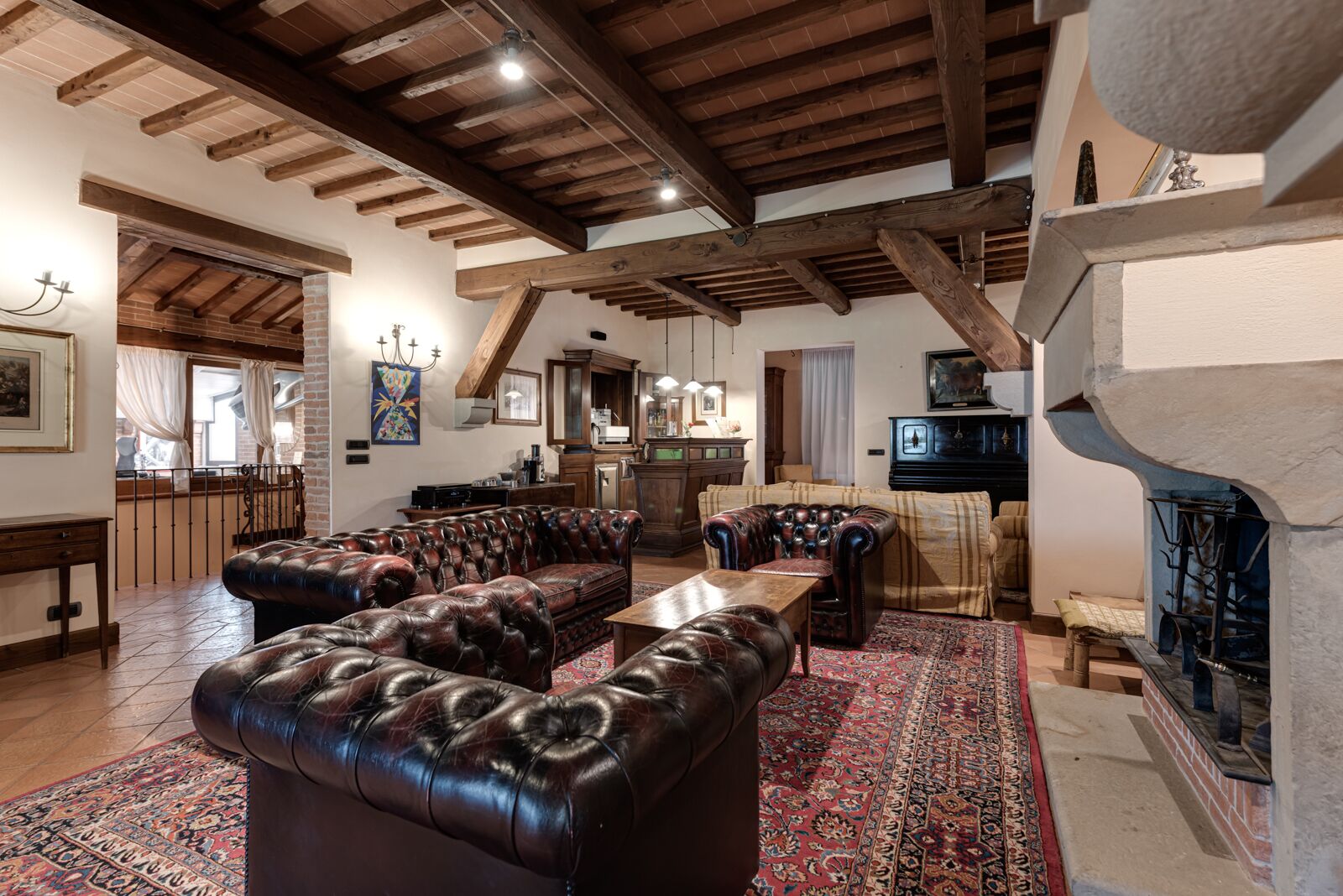 A spacious living room with leather sofas, a fireplace, and a kitchen in the background.
