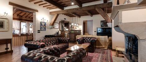 A spacious living room with leather sofas, a fireplace, and a kitchen in the background.