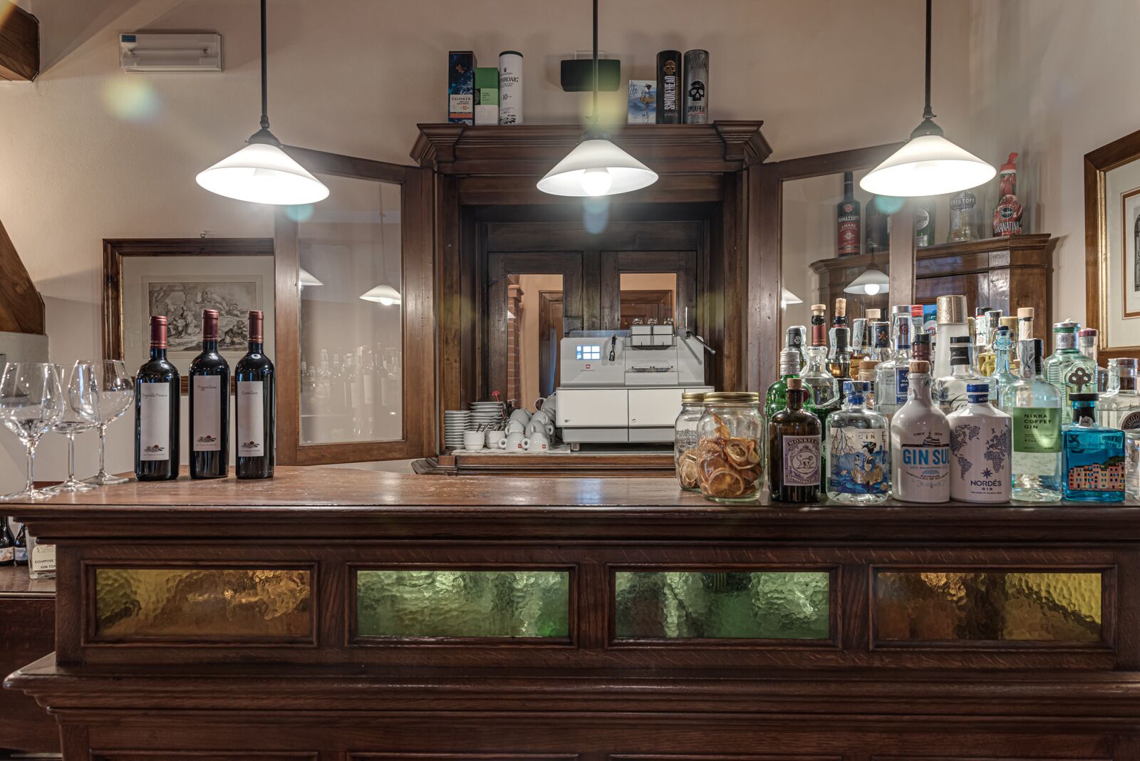 A bar area with a wooden counter, bottles of alcohol, and glasses.