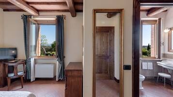Una stanza con un letto, una scrivania, un termosifone e una finestra con tende.