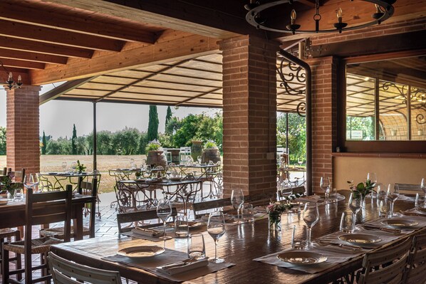An outdoor dining area with brick columns, metal chairs, and tables set for a meal.