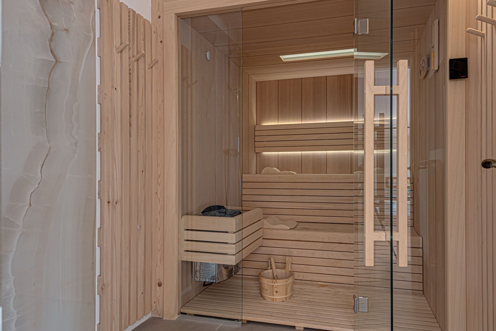 A sauna with wooden walls, a glass door, and a bench.
