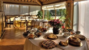Zona pranzo con tavolo apparecchiato per un pasto, circondata da finestre e un muro in mattoni.