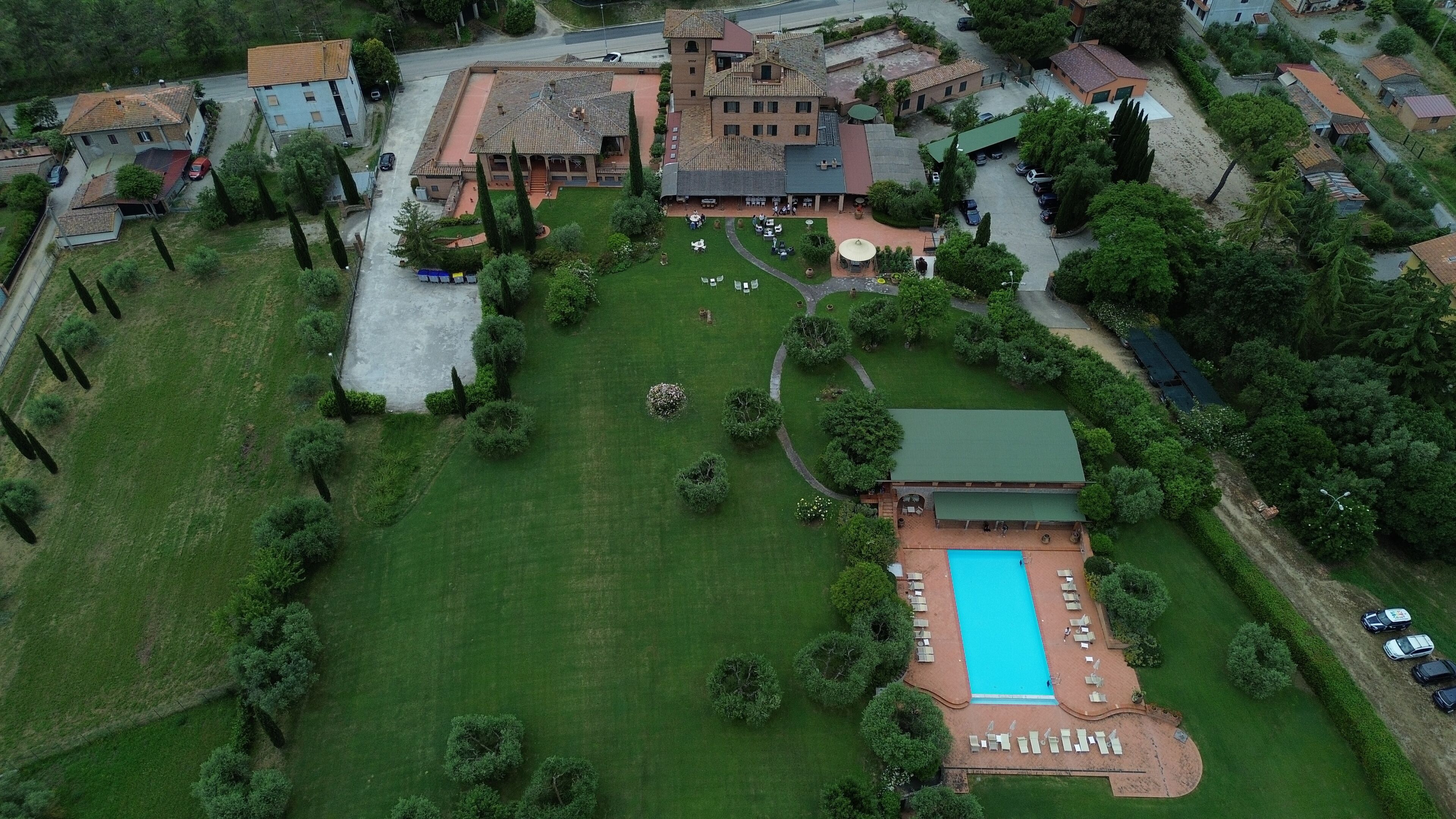 Vista aérea de un hotel con piscina, césped verde y zona de estacionamiento.