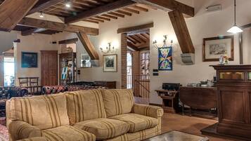 Un salón amplio con un sofá grande, vigas de madera, chimenea y comedor con mesa y sillas de madera.
