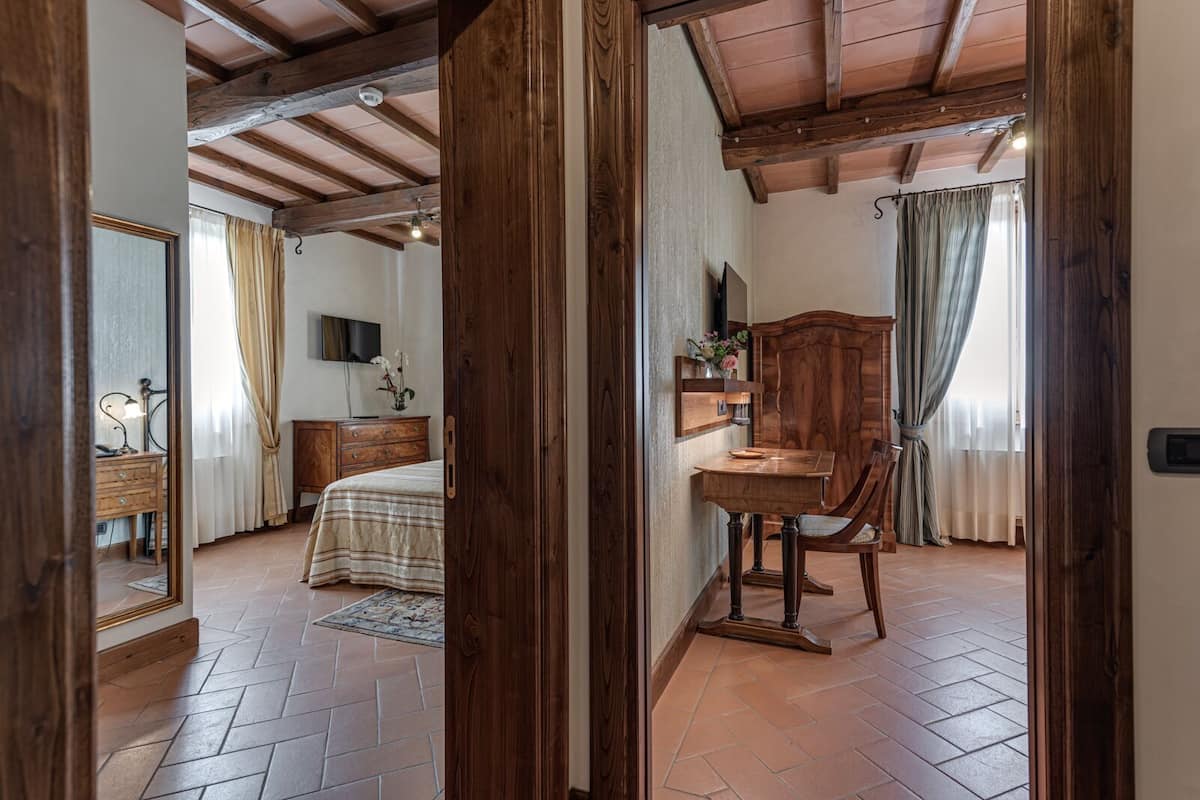 Une chambre à coucher comprenant un lit, une commode, un téléviseur et un bureau en bois avec une chaise.