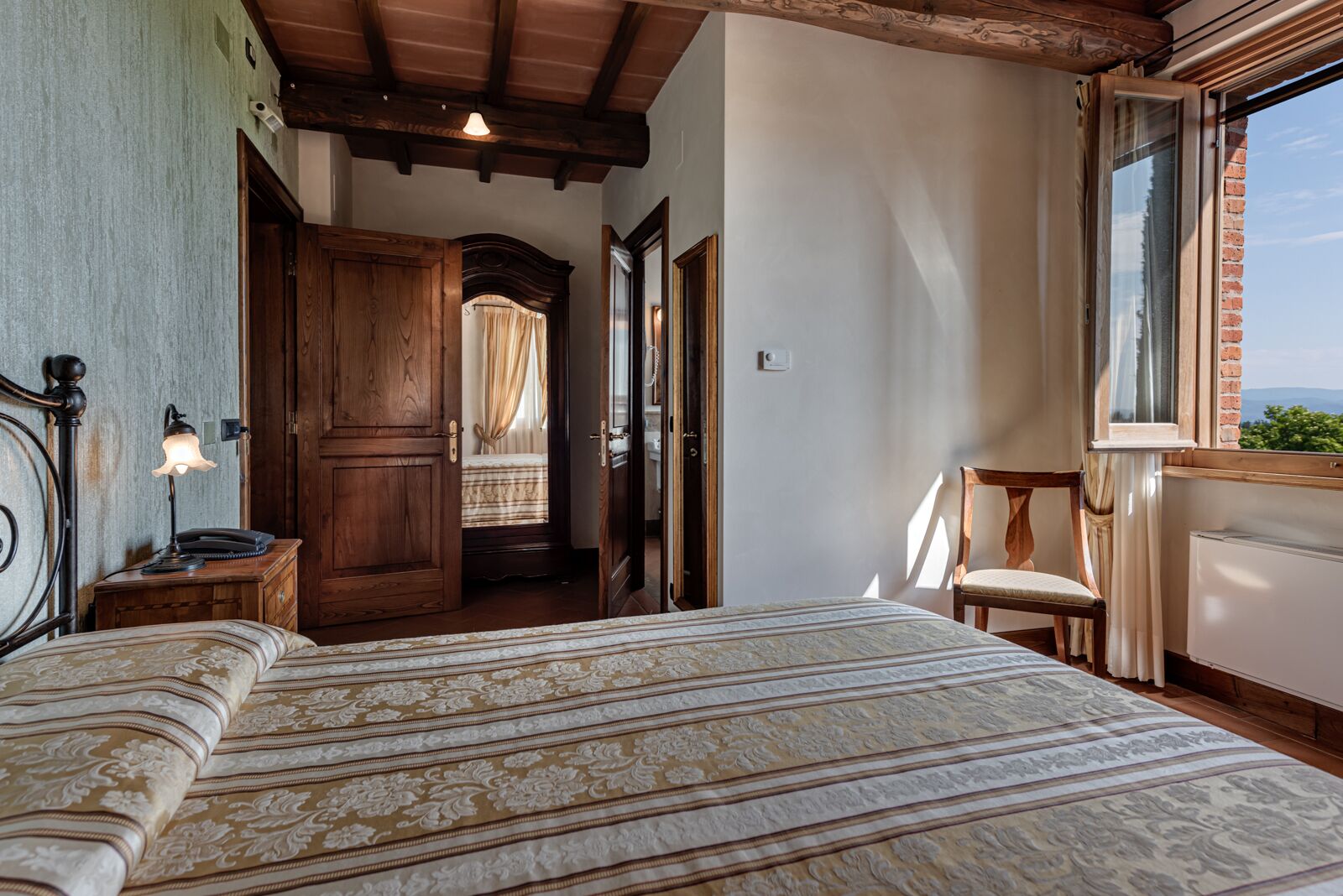 Une chambre avec un grand lit, une porte en bois et une fenêtre donnant sur un beau paysage.