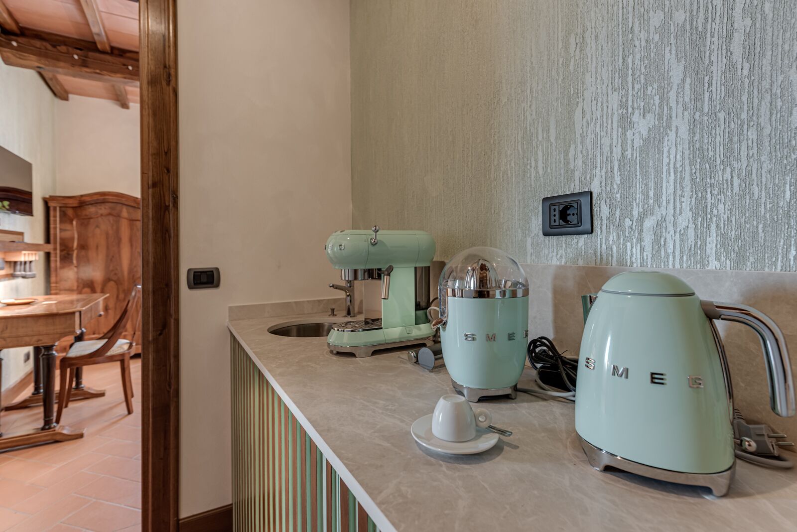 A kitchen with a countertop, a coffee maker, a kettle, and a sink.
