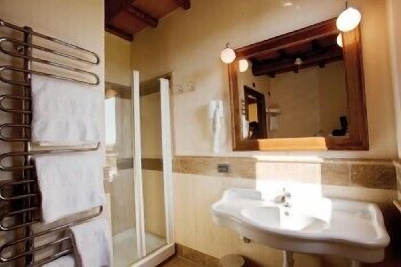 Een badkamer met een glazen douche, een wastafel en een handdoekrek.
