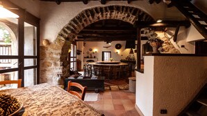A rustic dining area with a large table, chairs, and a stone archway. - Casa Migliaca (Pettineo)