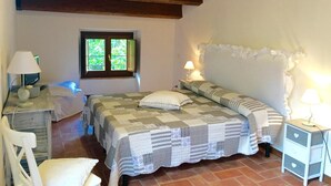 Une chambre à coucher comprenant un lit, deux tables de chevet, une chaise, une fenêtre donnant sur un beau paysage et un plafond en bois.