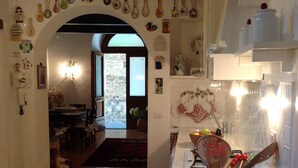 Une cuisine chaleureuse avec des meubles blancs, un luminaire suspendu et un arc en pierre rustique.