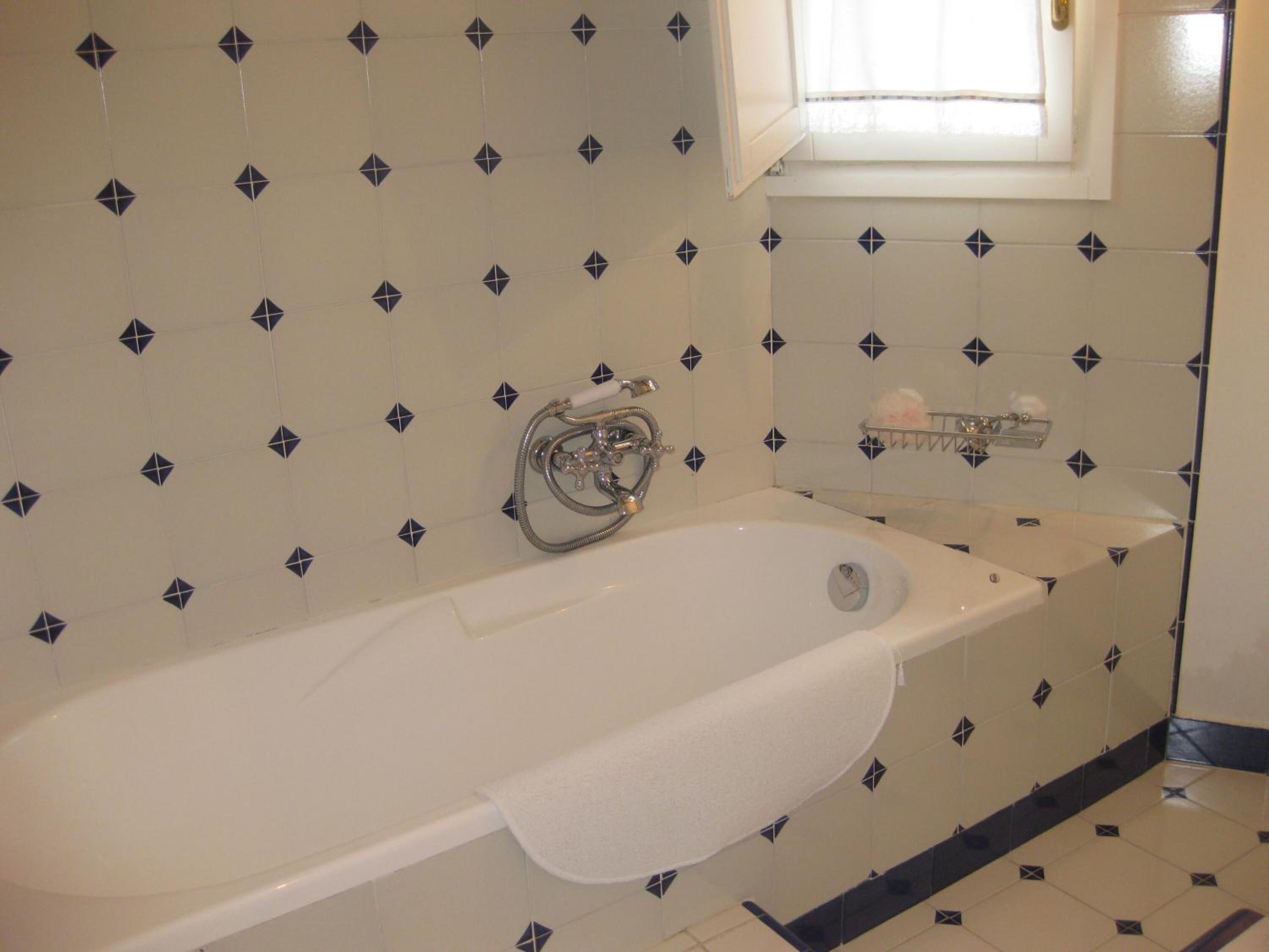 Un baño con bañera, ventana y toallero.