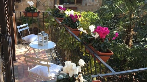Une terrasse avec des sièges extérieurs, des plantes en pot et une vue sur un bâtiment en pierre.
