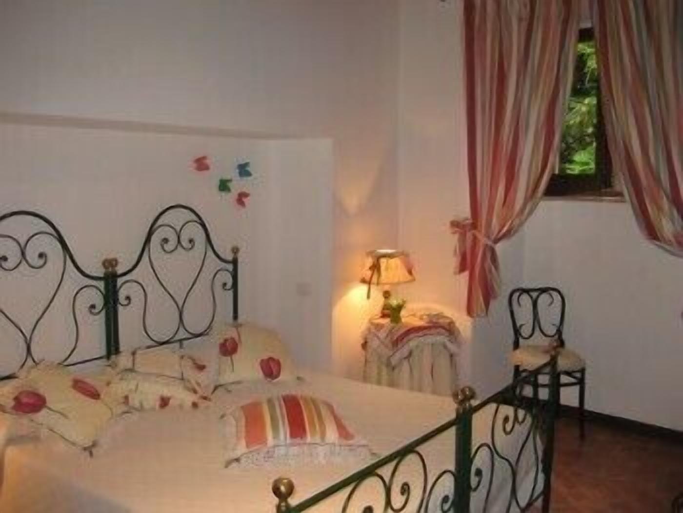 A bedroom with a bed, a chair, a lamp, and a window with curtains.