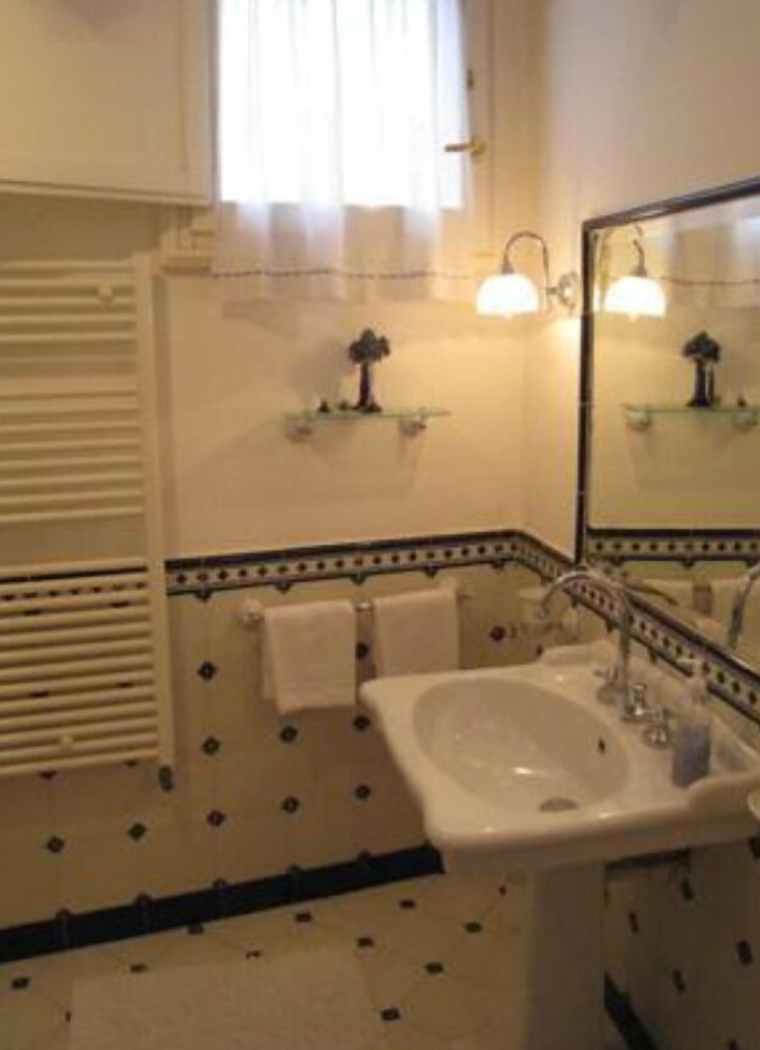 A bathroom with a sink, mirror, towel rack, and patterned floor tiles.
