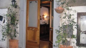 Une entrée d’immeuble avec une porte en bois, un arc en pierre et des plantes en pot de chaque côté.