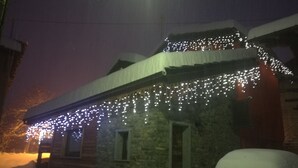 Un edificio de piedra con nieve en el techo y luces colgantes.