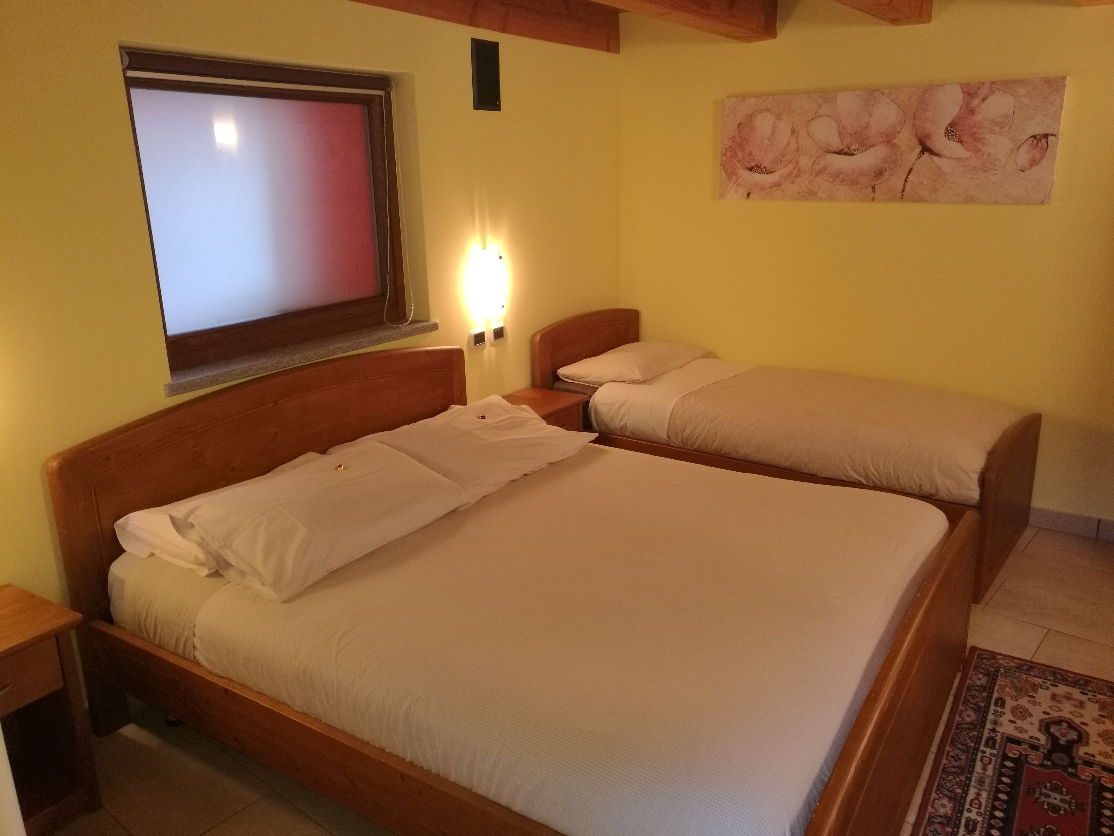 A room with two beds, a TV, and a painting on the wall.