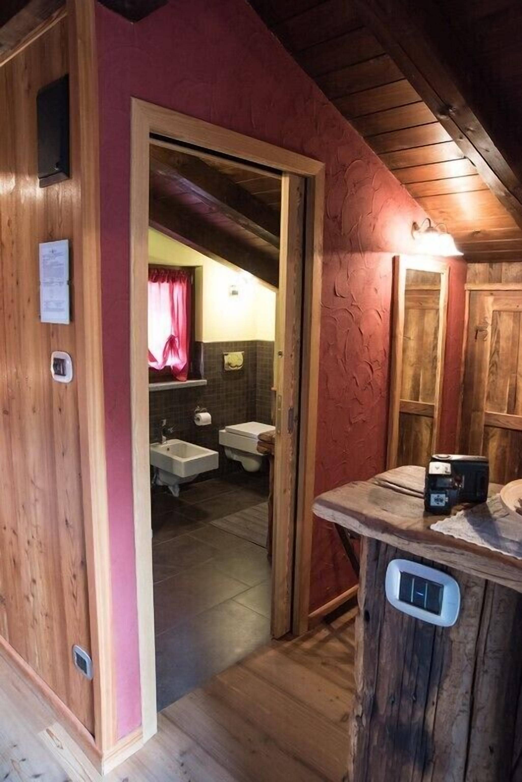 Een houten badkamer met een houten deur, een wastafel en een spiegel.