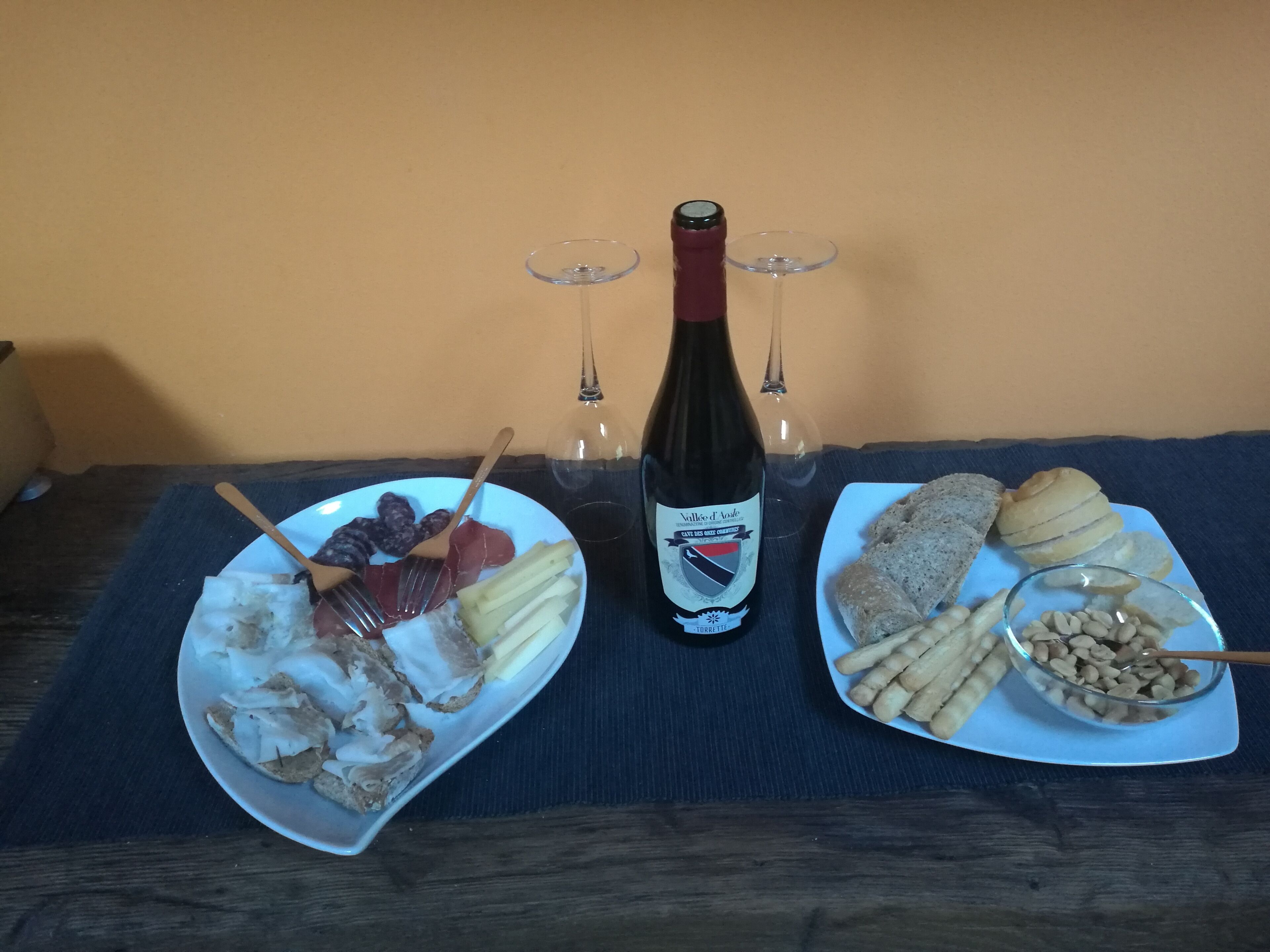 Twee borden eten, een fles wijn en twee wijnglazen op een tafel.