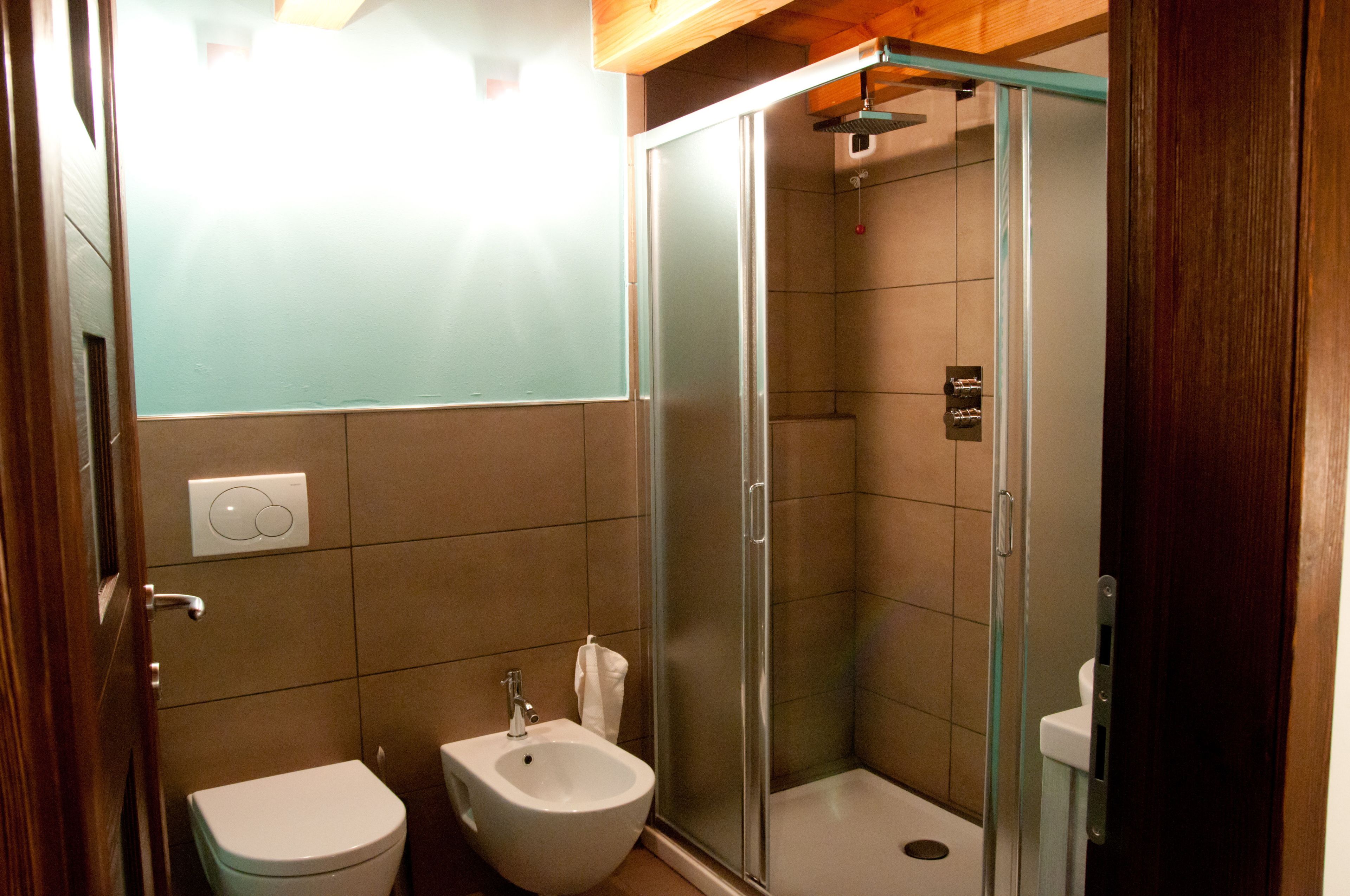 A bathroom with a toilet, bidet, and glass-enclosed shower.