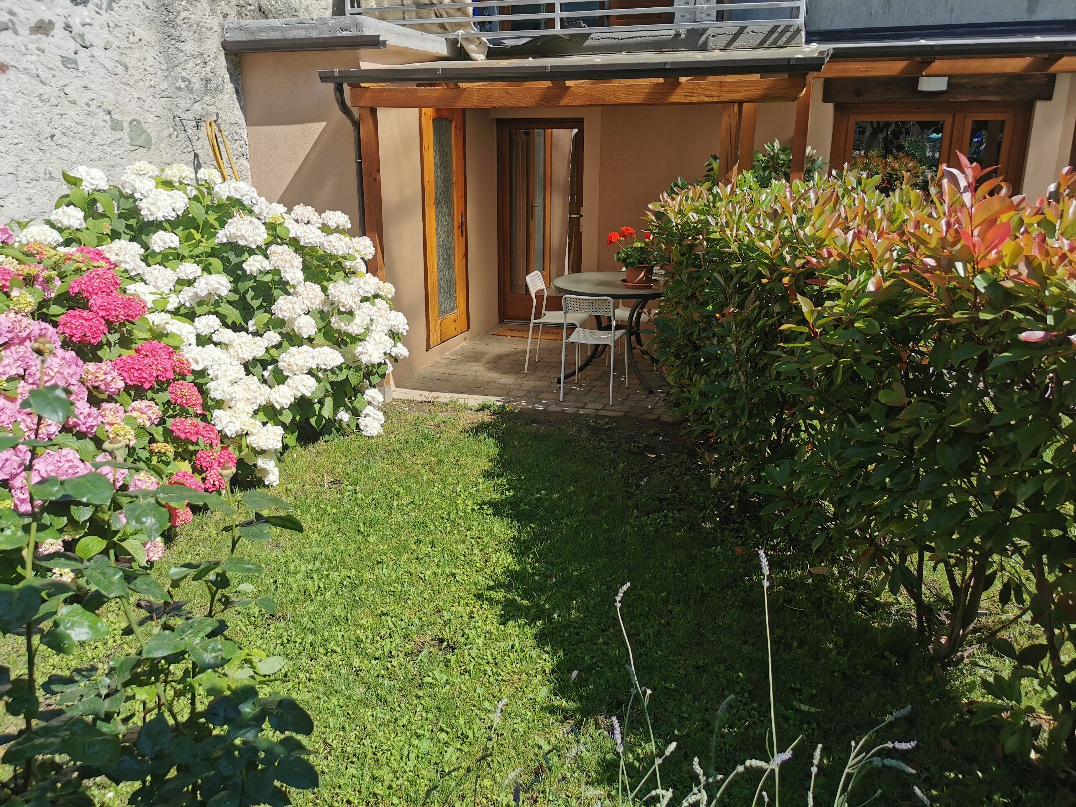 Ein Garten mit einer Terrasse, einem Tisch und Stühlen.
