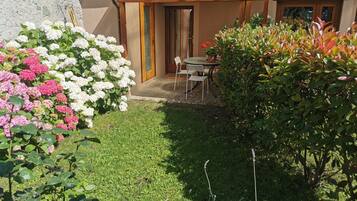Ein Garten mit einer Terrasse, einem Tisch und Stühlen.