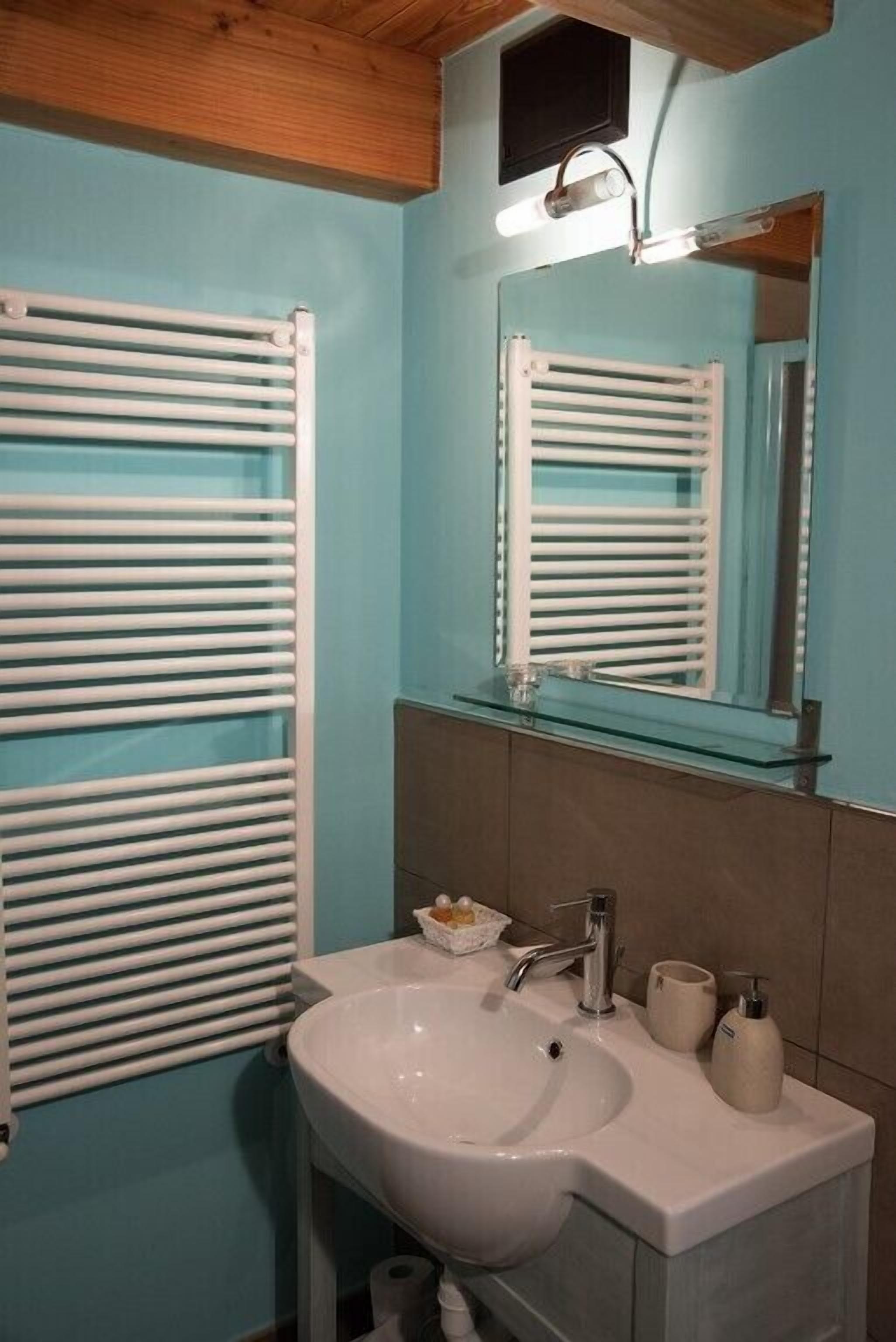 A bathroom with a white sink, a mirror, and a towel rack.