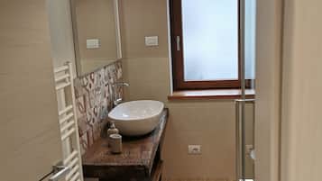 A bathroom with a large sink, a mirror, a window, and a towel rack.
