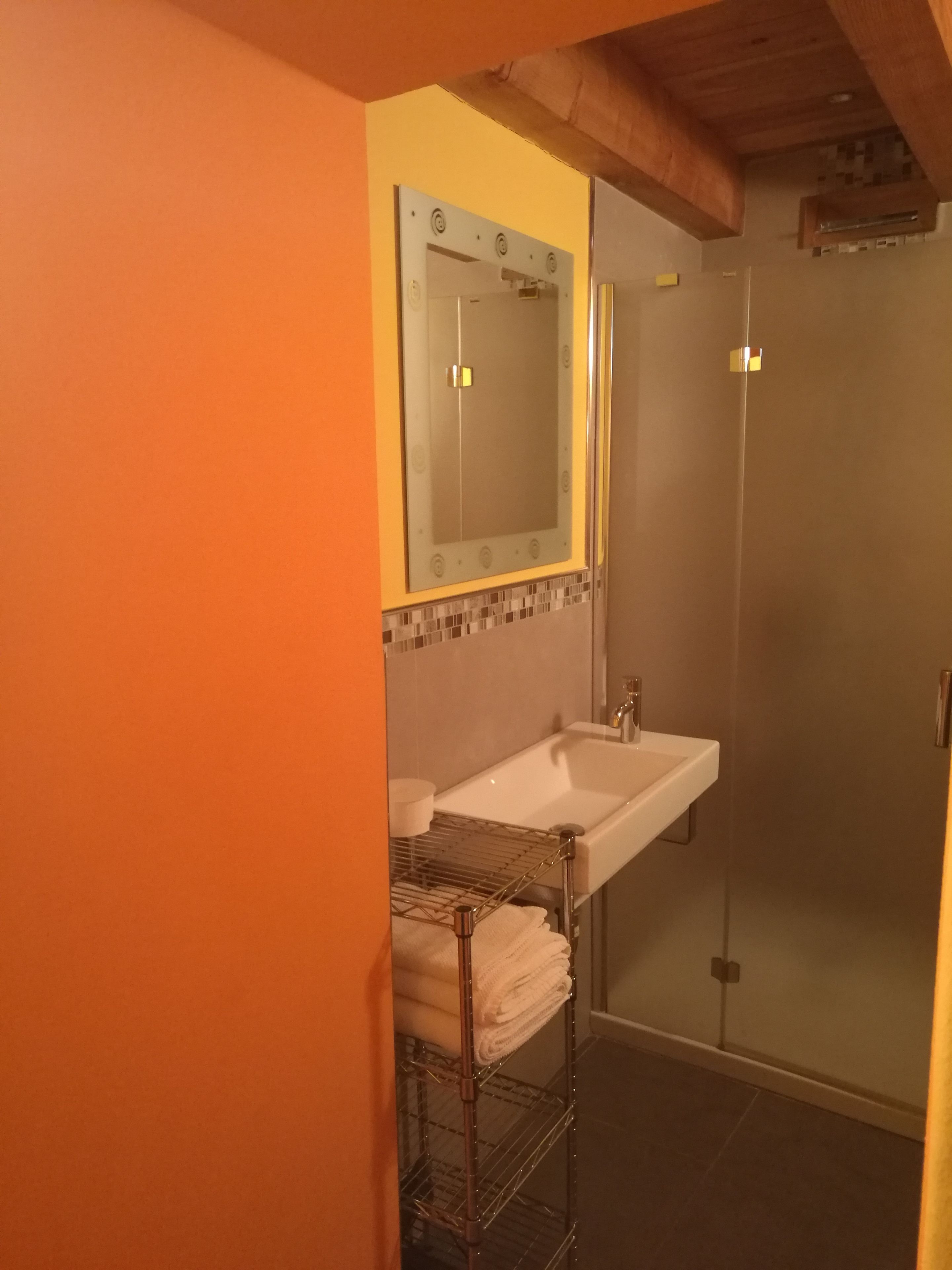 Un baño con lavamanos blanco, espejo y ducha.