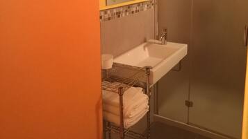 Un baño con lavamanos blanco, espejo y ducha.