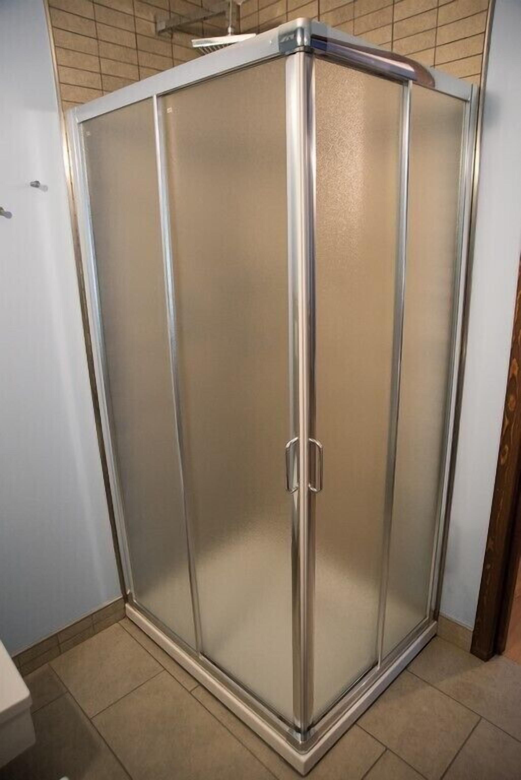 Box doccia angolare con porta in vetro satinato e struttura cromata.
