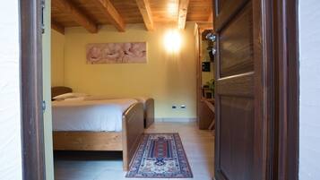 Una camera da letto con soffitto in legno, un letto, un tappeto e un quadro appeso al muro.