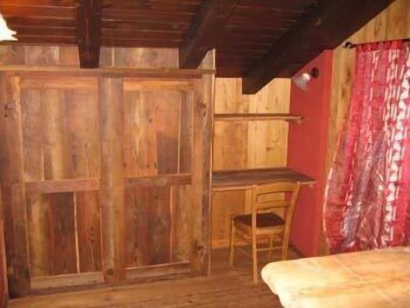 Una habitación rústica de madera con una cama, un escritorio y una silla.