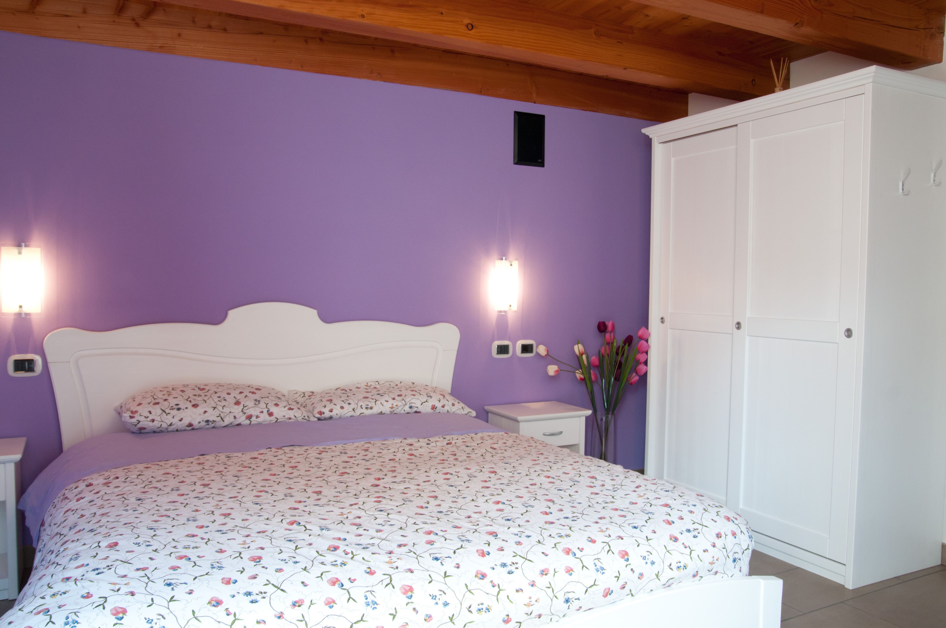 Une chambre à coucher comprenant un lit, des tables de chevet, une armoire et des lampes fixées au mur.