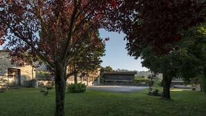 Une cour avec un arbre, un bâtiment en pierre et une structure en bois.