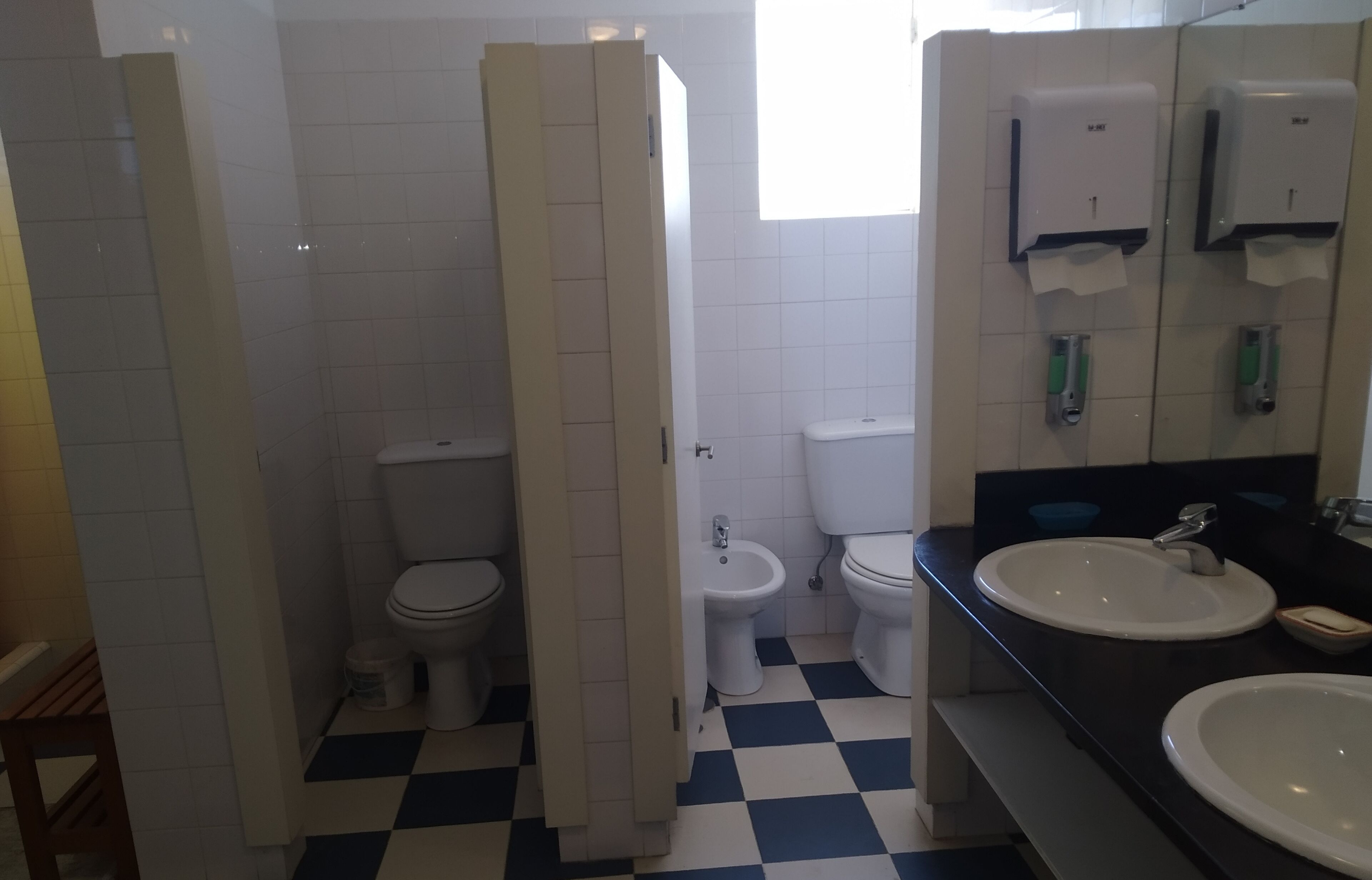 A bathroom with two toilets, a bidet, and a sink with a mirror.