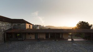 Un bâtiment rustique en pierre, doté d’un toit en tuiles et d’un patio couvert.