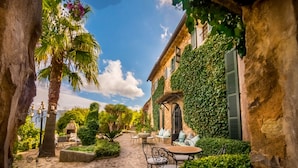Un patio con muros de piedra, una palmera y mobiliario para exterior.