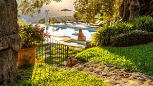 Un área de piscina con sillas de descanso, una estatua y una planta en maceta.