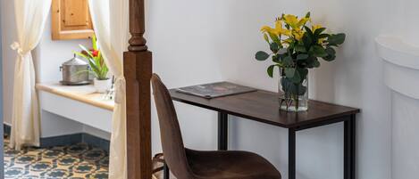 A small wooden desk with a chair, a vase with yellow flowers, and a book on the desk.