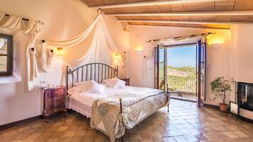 Ein Schlafzimmer mit Bett, Nachttisch, Fenster und Blick ins Freie.